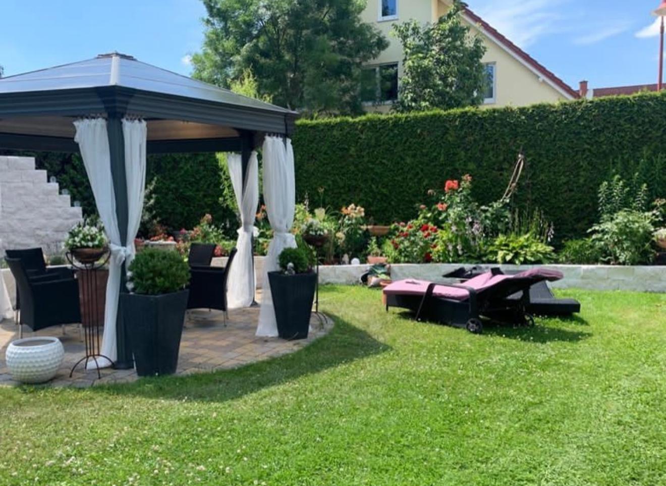 Gestalteter Garten mit Pavillon, Bepflanzung und gepflegtem Rasen