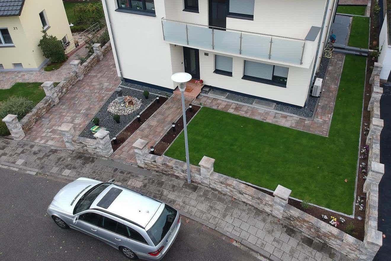 Neu angelegter Vorgarten mit Pflasterung, Natursteinmauern und frischem Rollrasen von YOTEK Garden Design
